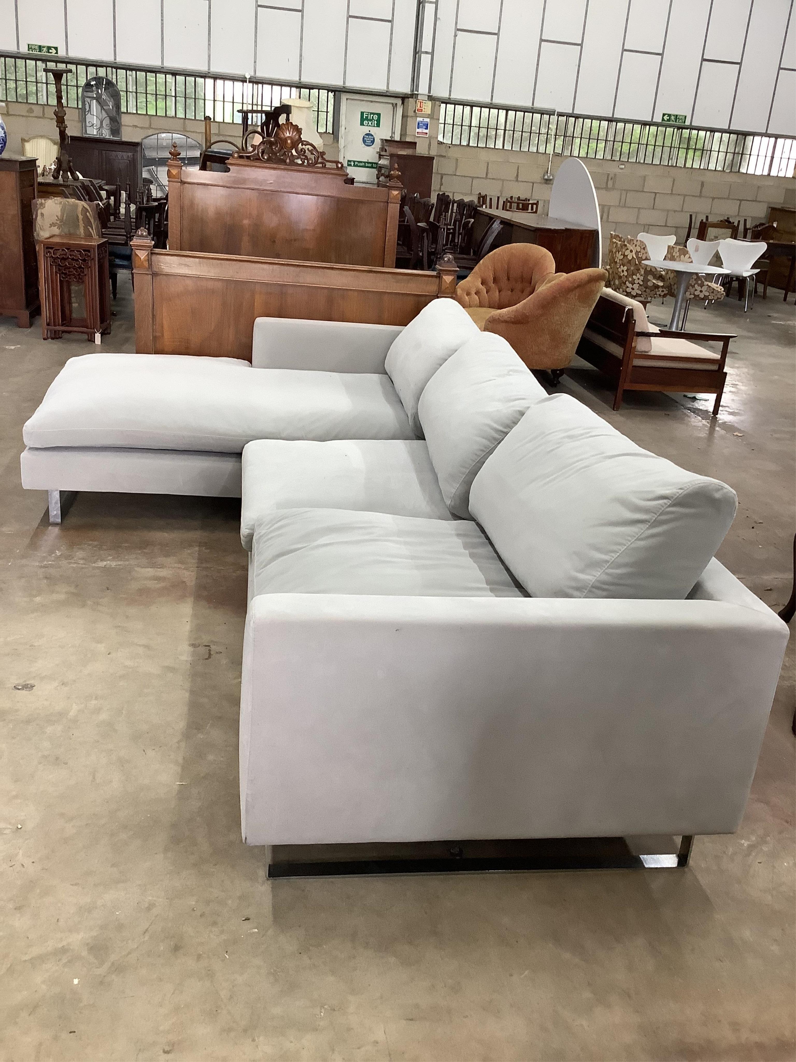 A pale grey fabric upholstered L shaped settee with chromed feet, width 304cm, height 190cm. Condition - fair